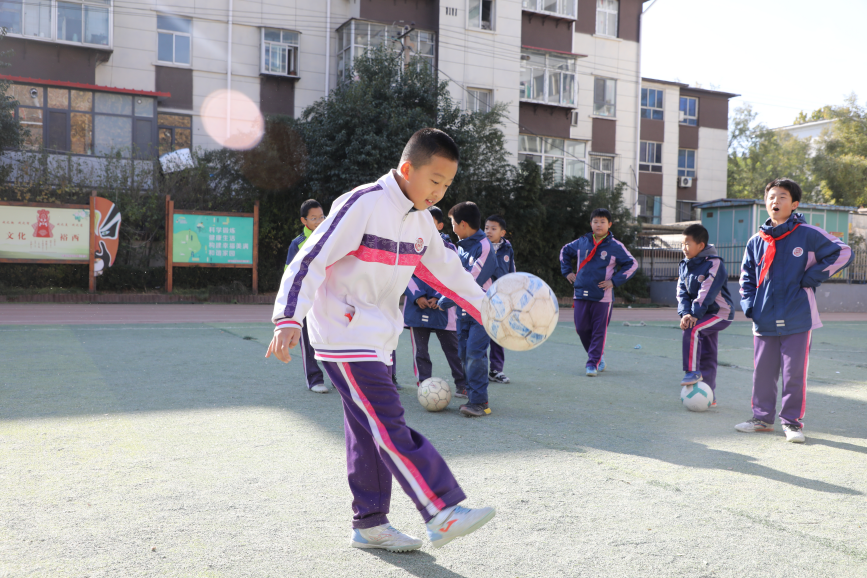 課間的操場上，學生們聚在一起踢足球玩耍。 吳夢瑩攝
