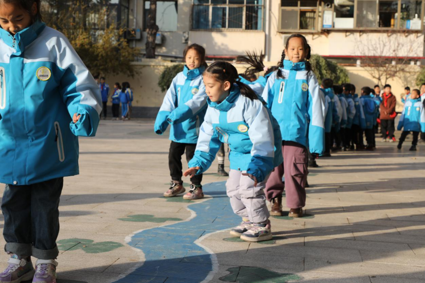 學生們在校園裡畫出的游戲活動區中蹦跳玩耍。 吳夢瑩攝