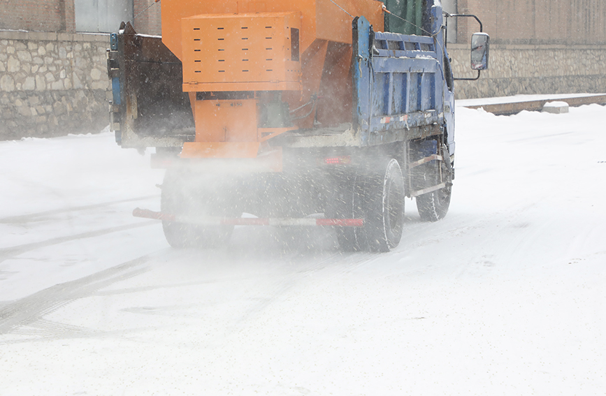 撒布机在道路上喷洒颗粒状融雪剂。 白天龙摄