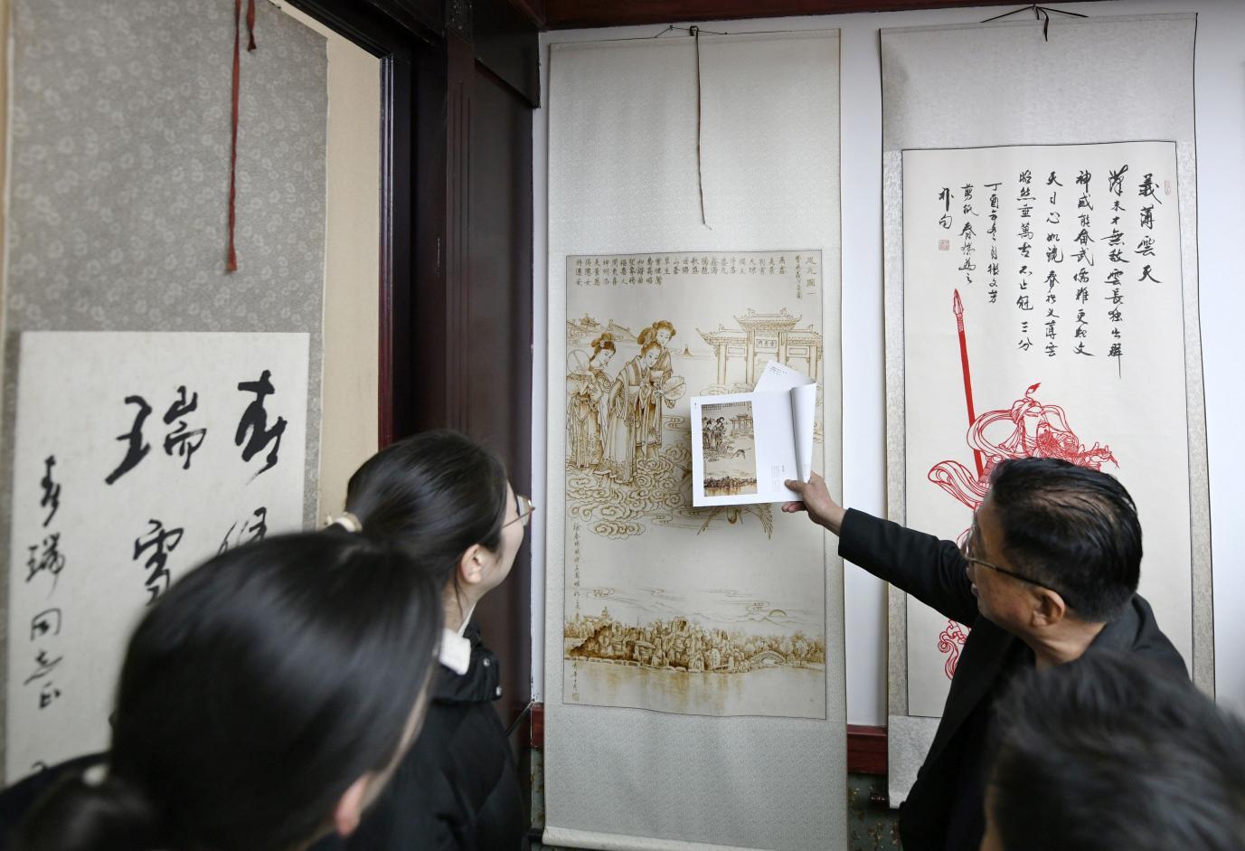 在迁安市文化展示类名家工作室——春瑞书院，院长徐春瑞给参观人员讲解字画。