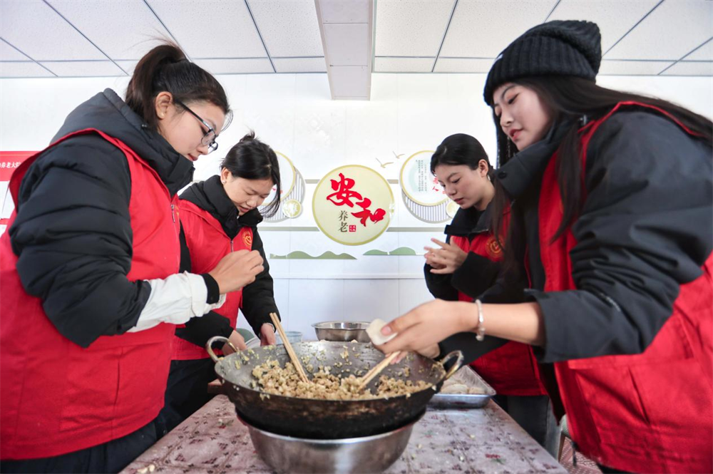 在河北省唐山市豐南區東田庄鄉崔庄戶村文化禮堂，青年志願者們正在為老人包餃子。 畢帥攝