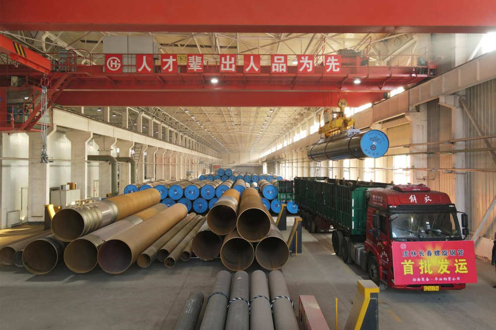 工人操作起重机将钢管装入发运车。 尹向平摄
