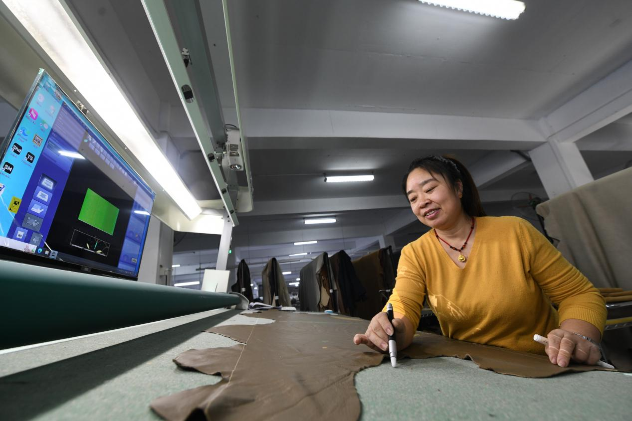 在文安县现代家居制造产业园河北法远家具有限公司，工人正在对皮革划线裁剪。 郑佳庆摄