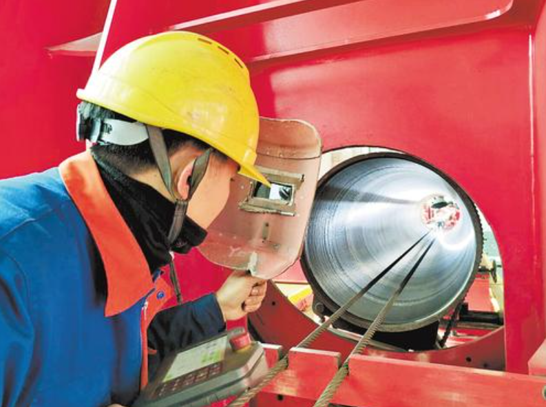 近日，沧州隆泰迪管道科技有限公司工作人员在生产线上观察堆焊加工过程。 河北日报记者 戴绍志摄