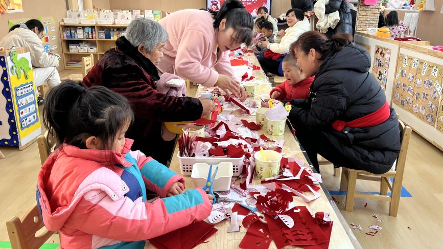 家長和孩子們一起剪紙。馬靜攝