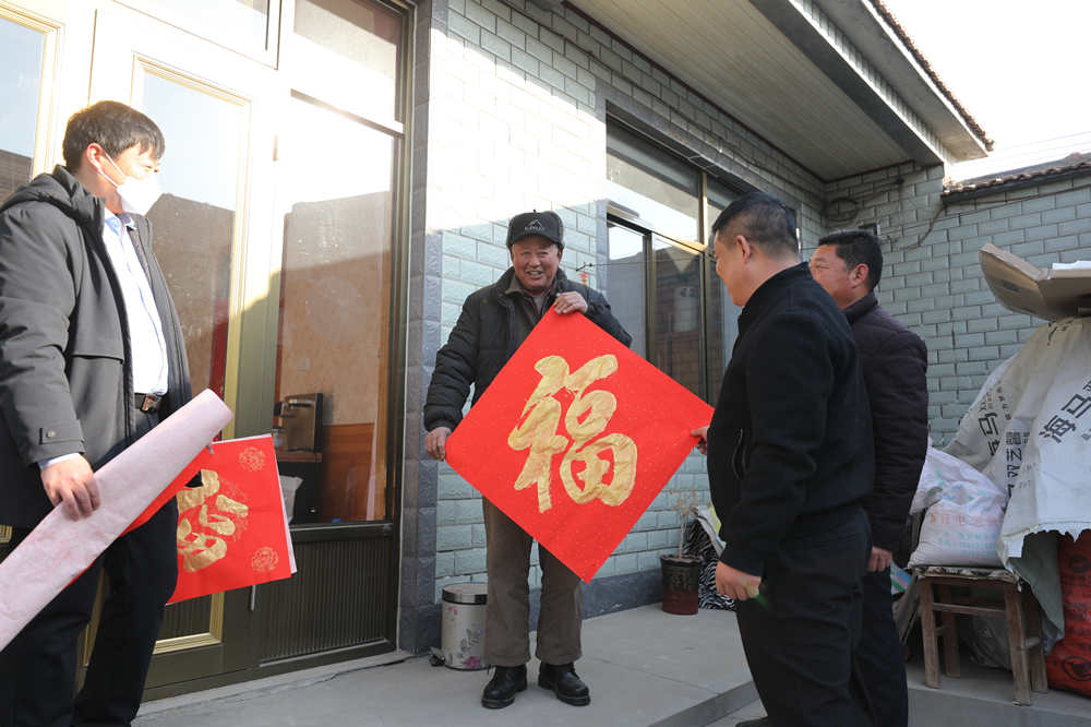 村干部把春联、福字送到村民家中。田博摄