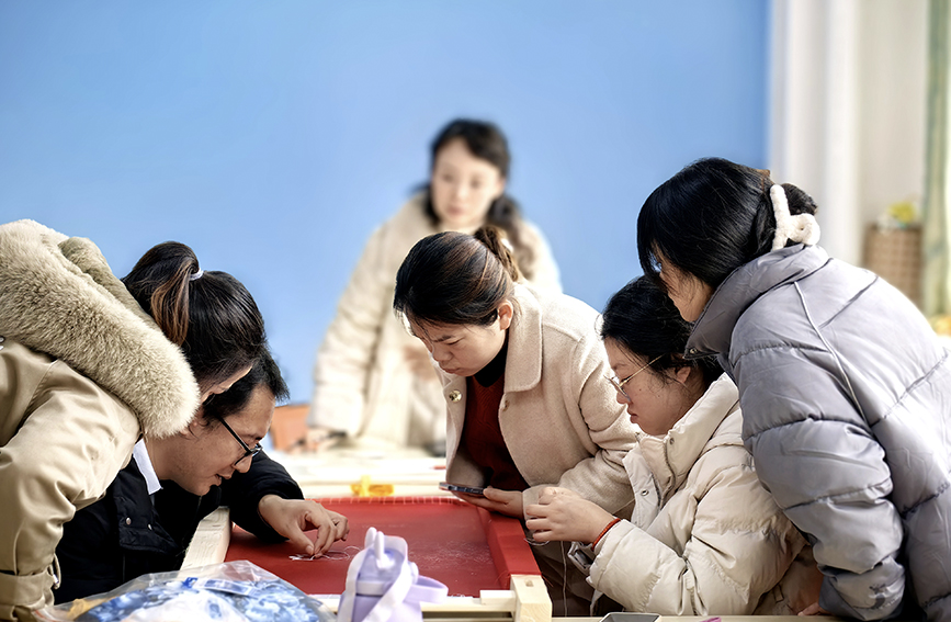 学生认真观看陈芳刚现场刺绣。苏培摄