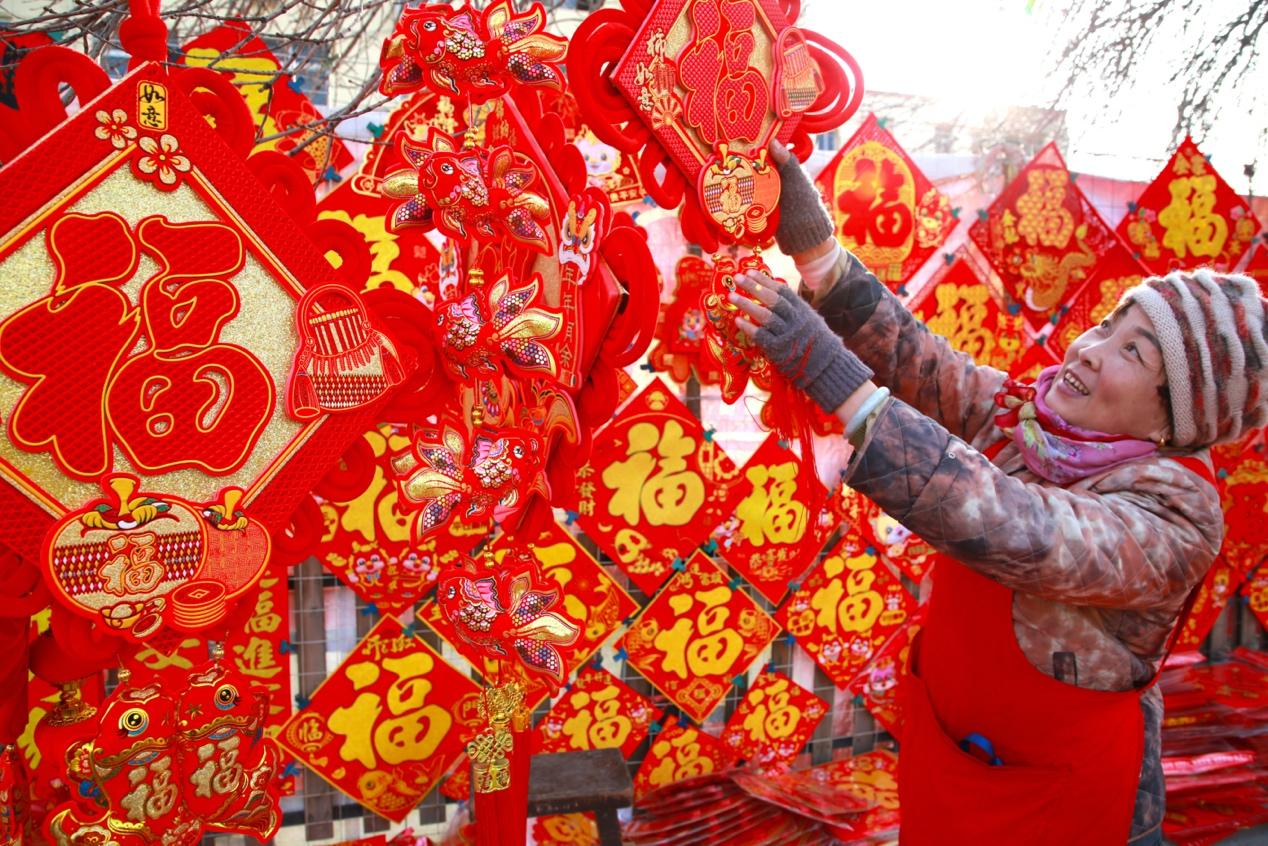 2月1日，在河北沧州市光荣路对联市场内，一名商家正在整理“福”字。殷实摄