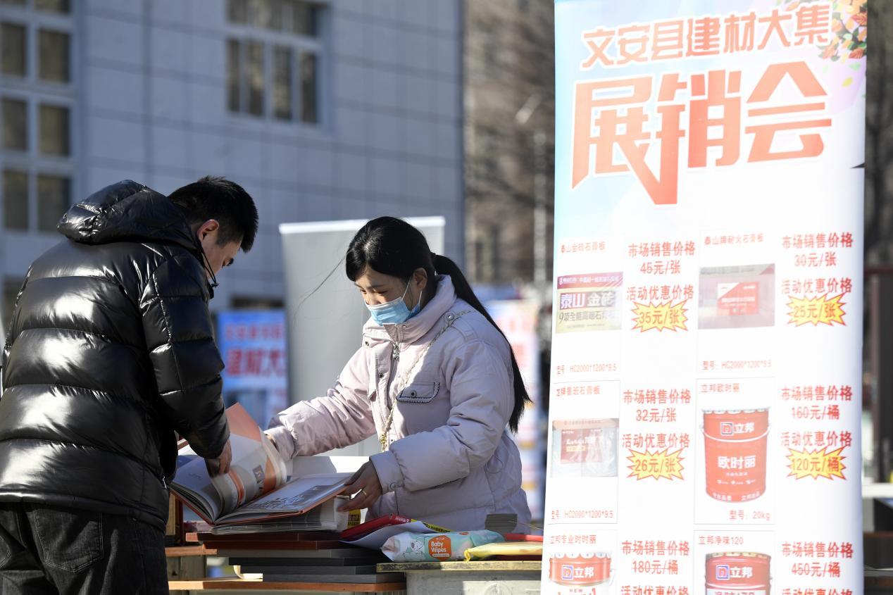在文安县新镇镇芦阜庄村“建材大集”活动现场，当地建筑企业工作人员（右一）正在向村民介绍产品。王晖摄