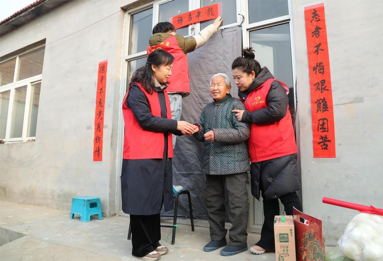 志愿者为孤寡老人贴春联。陈英华摄