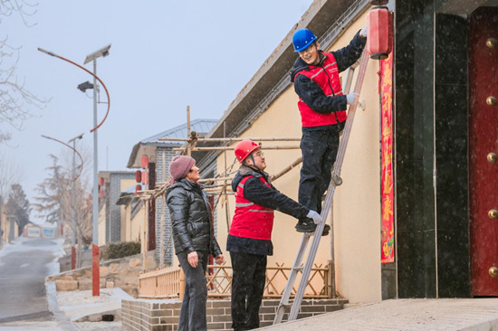 国网平山县供电公司员工在北庄村帮助村民挂灯笼、贴春联。霍晓娟摄