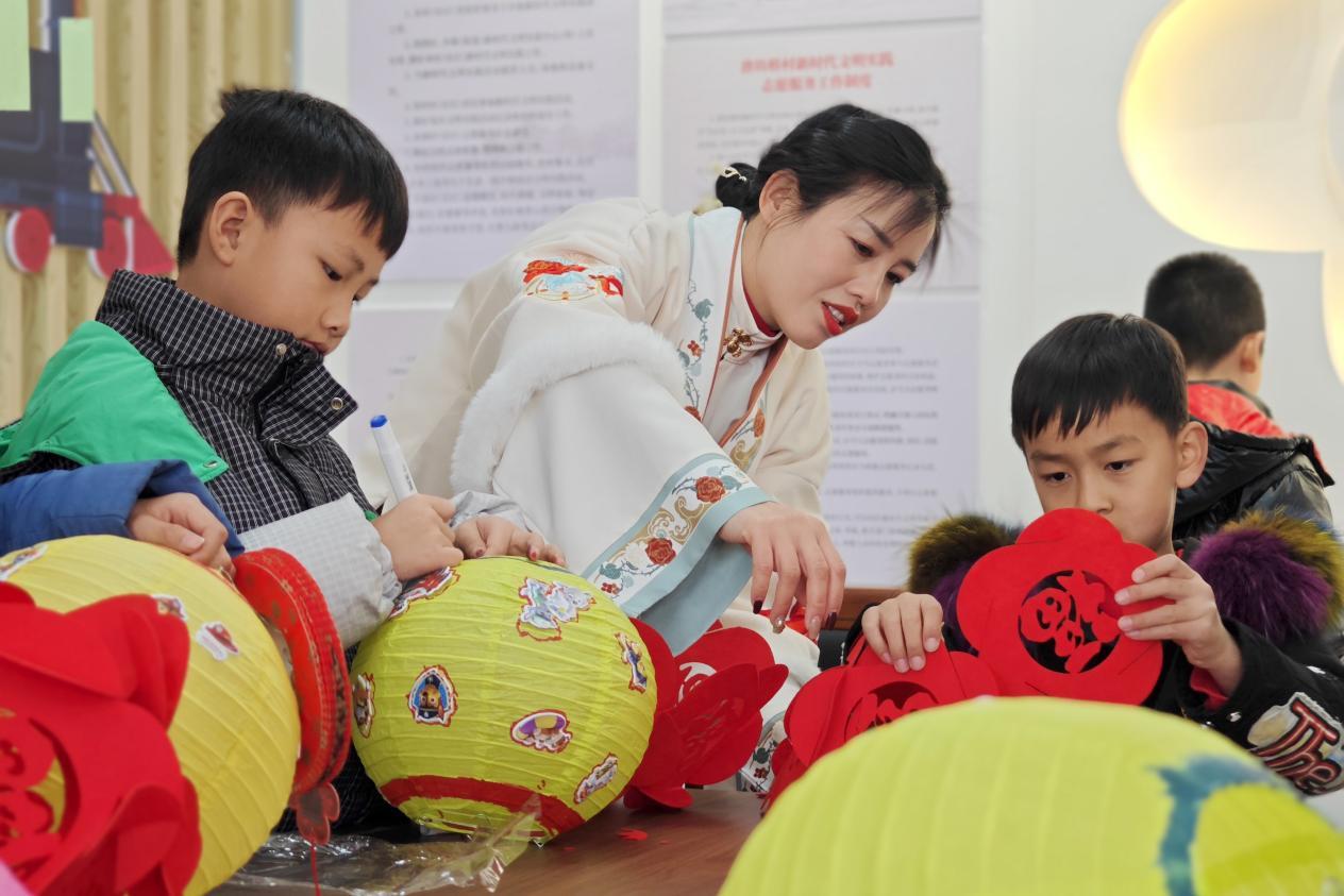 在唐山市豐南區唐坊鎮新時代文明實踐所，志願者正在教孩子們制作花燈。張杰攝