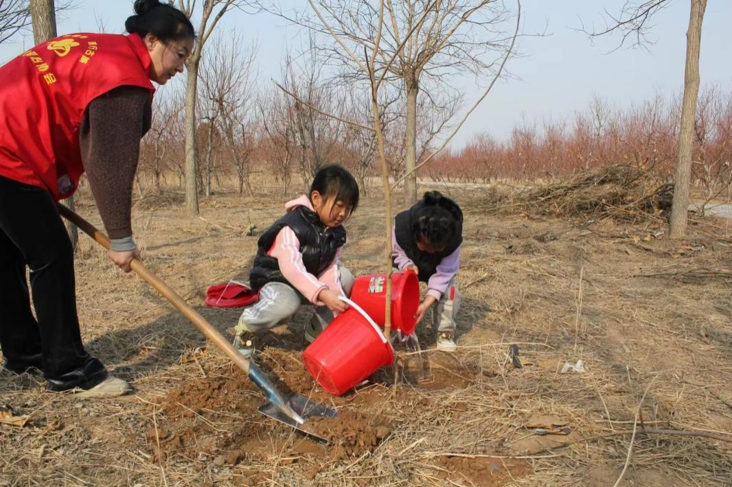 孩子澆水,母親培土,和諧一家植樹忙。南寶通攝
