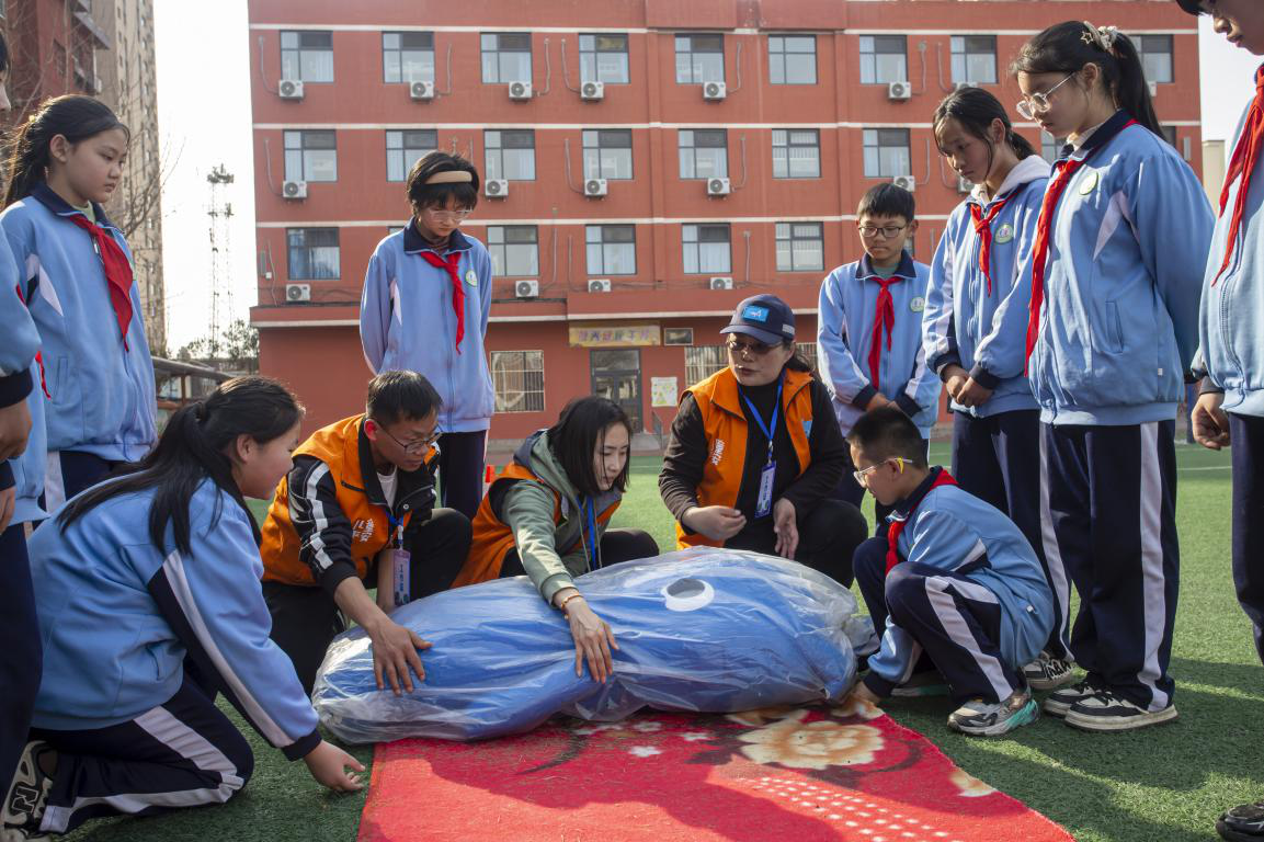 邯郸市红十字中安防减灾服务中心志愿者教孩子们使用毛毯担架方法。聂长青摄