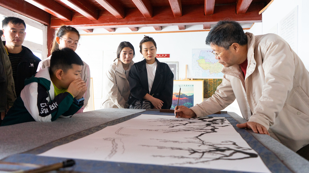 4月5日,河北省灤平縣金山嶺長城杏花活動,畫家吳建潮在創作金山嶺長城杏花相關國畫。灤平縣委宣傳部供圖