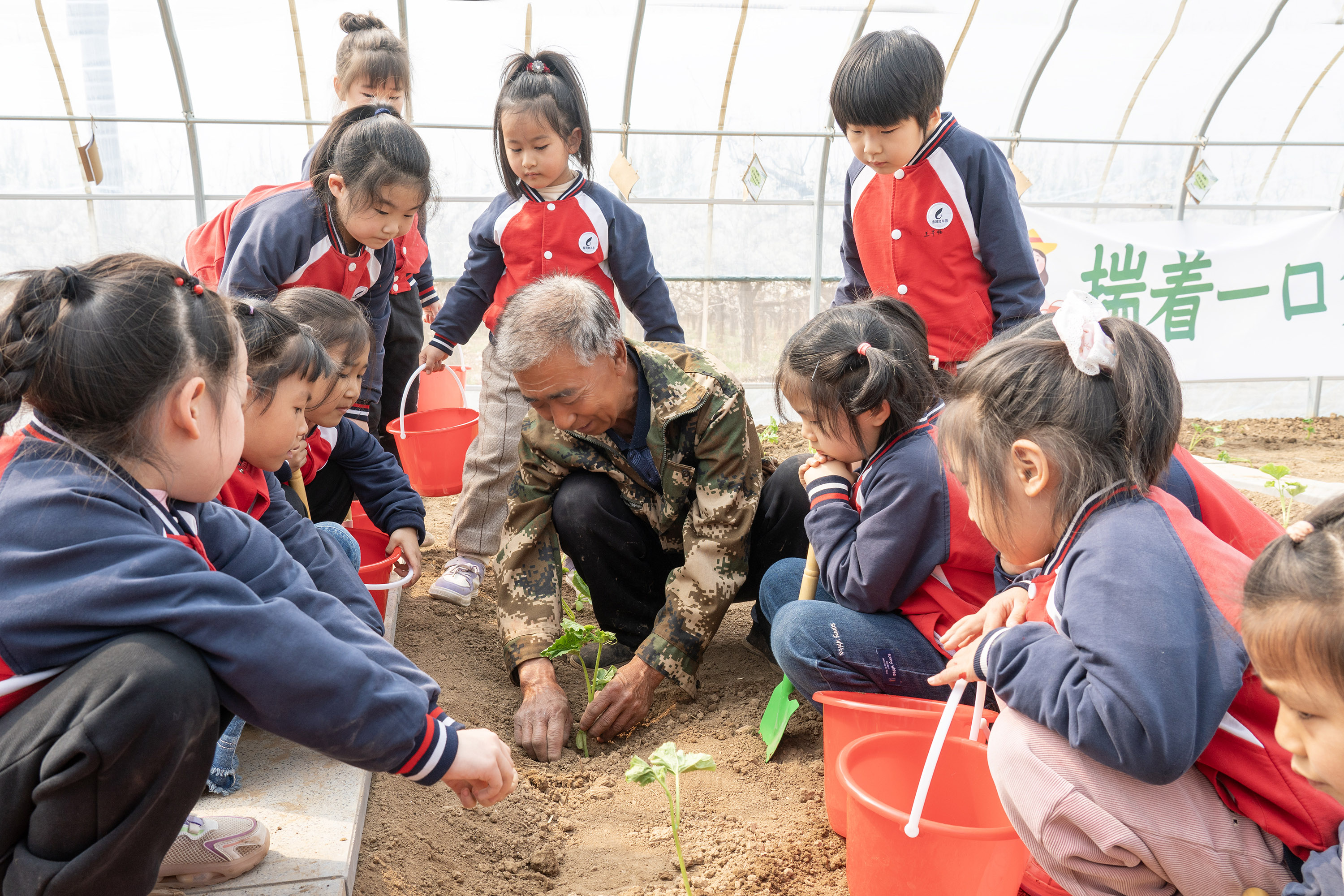 4月9日，高陽縣宏潤幼兒園小朋友走進閑野農庄開展種植實踐活動，魏愛國給孩子們示范種植秧苗。司秀花攝