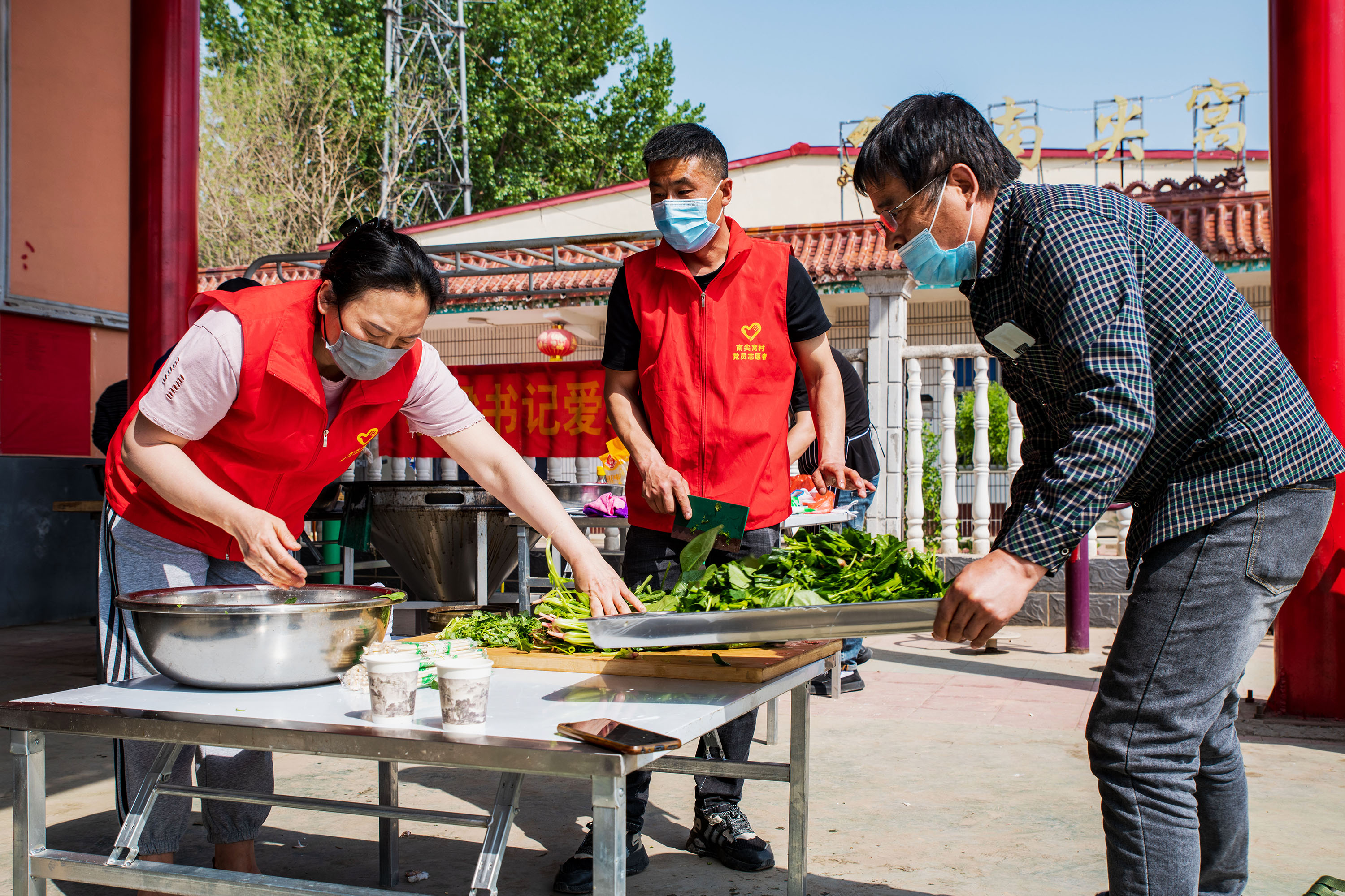 4月17日，在高阳县南尖村乡村大舞台前，志愿者切菜。芦建勇摄