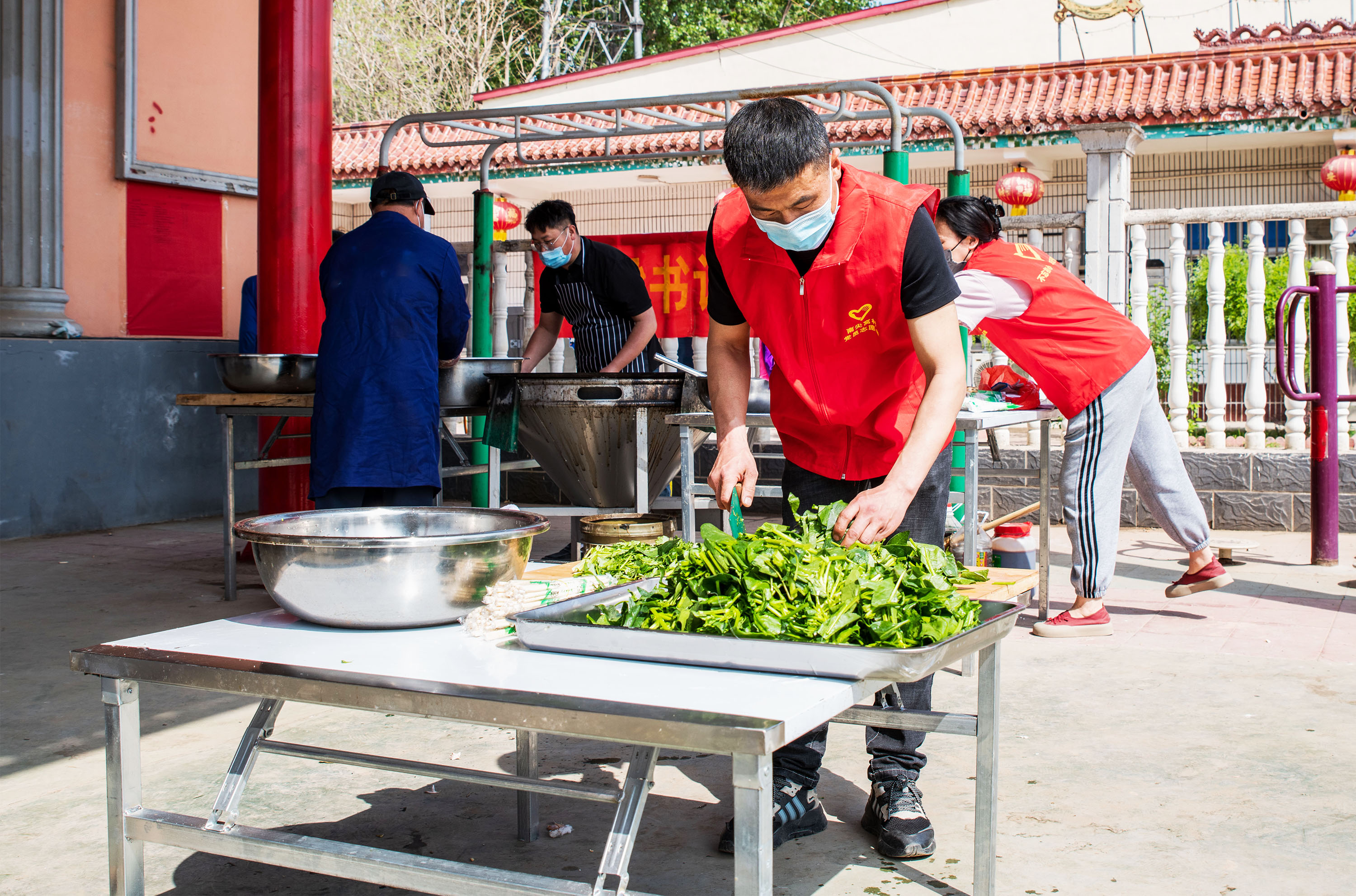 4月17日，在高阳县南尖村乡村大舞台前，志愿者切菜。芦建勇摄