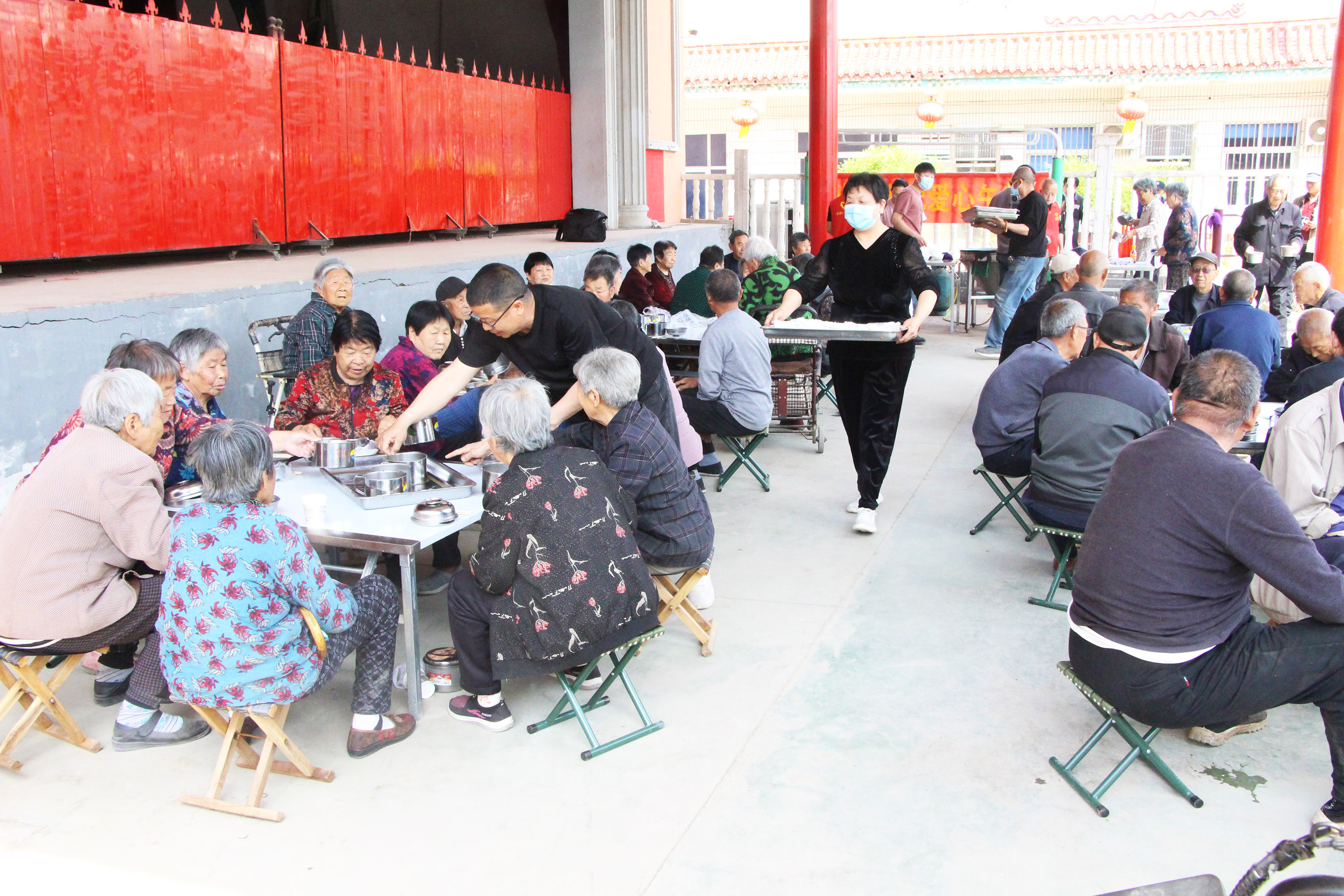 4月17日，在高阳县南尖村，志愿者将爱心午餐送到桌前，分发给每位老人。芦建勇摄