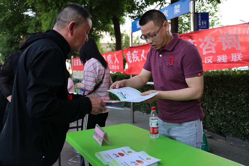 桥西区残疾人联合会工作人员为群众进行残疾预防知识普及。董璐摄