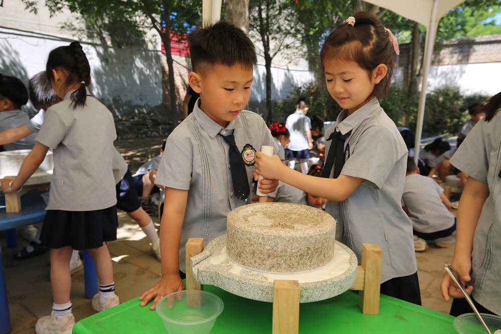 5月15日,小朋友们团结协作磨浆。李继业摄