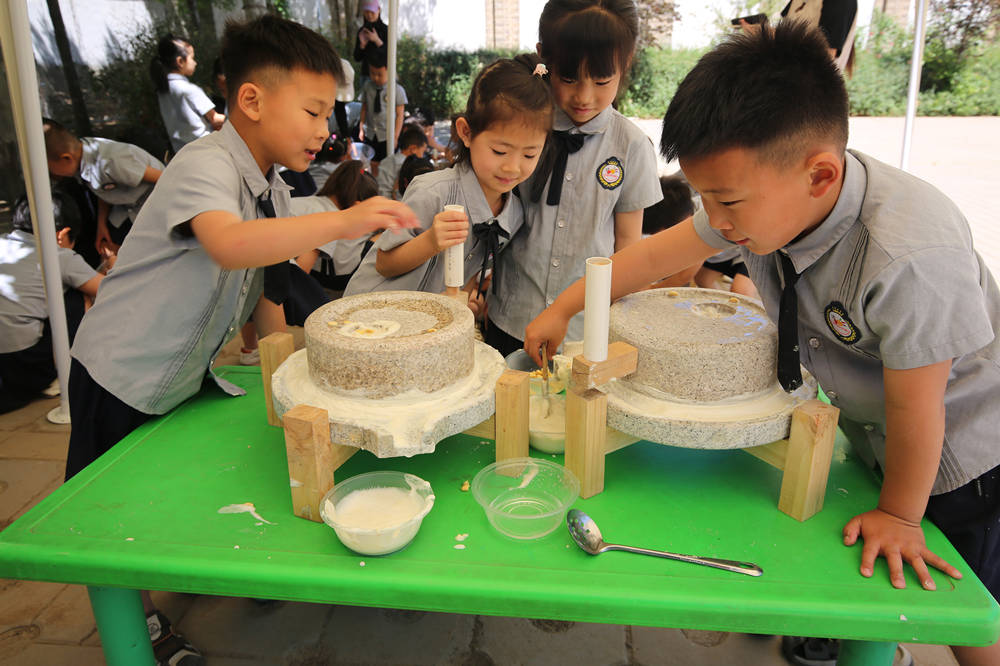 5月15日,小朋友们团结协作磨浆。李继业摄