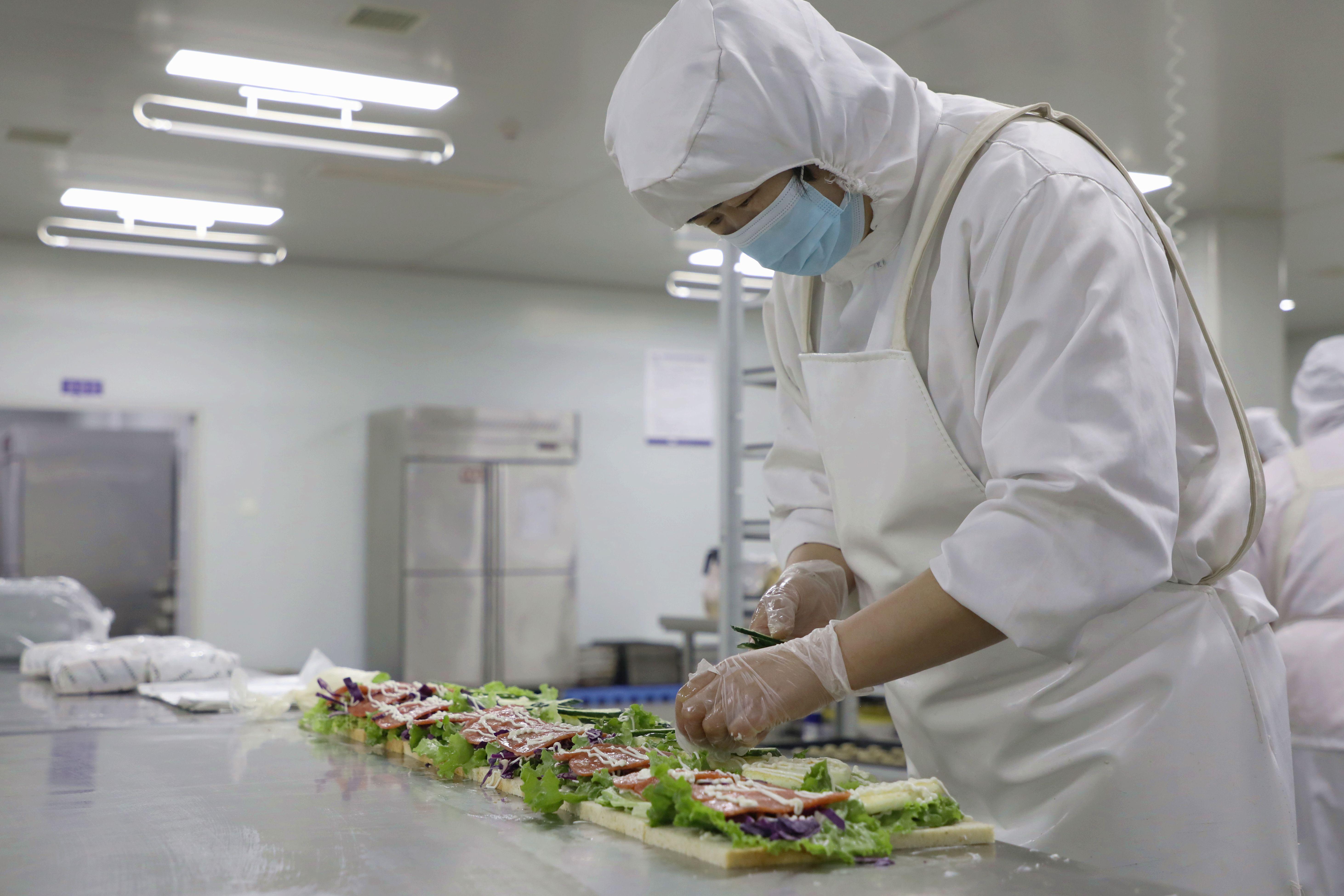 在香河县一食品厂生产车间，糕点师在制作三明治。朱钰爽摄