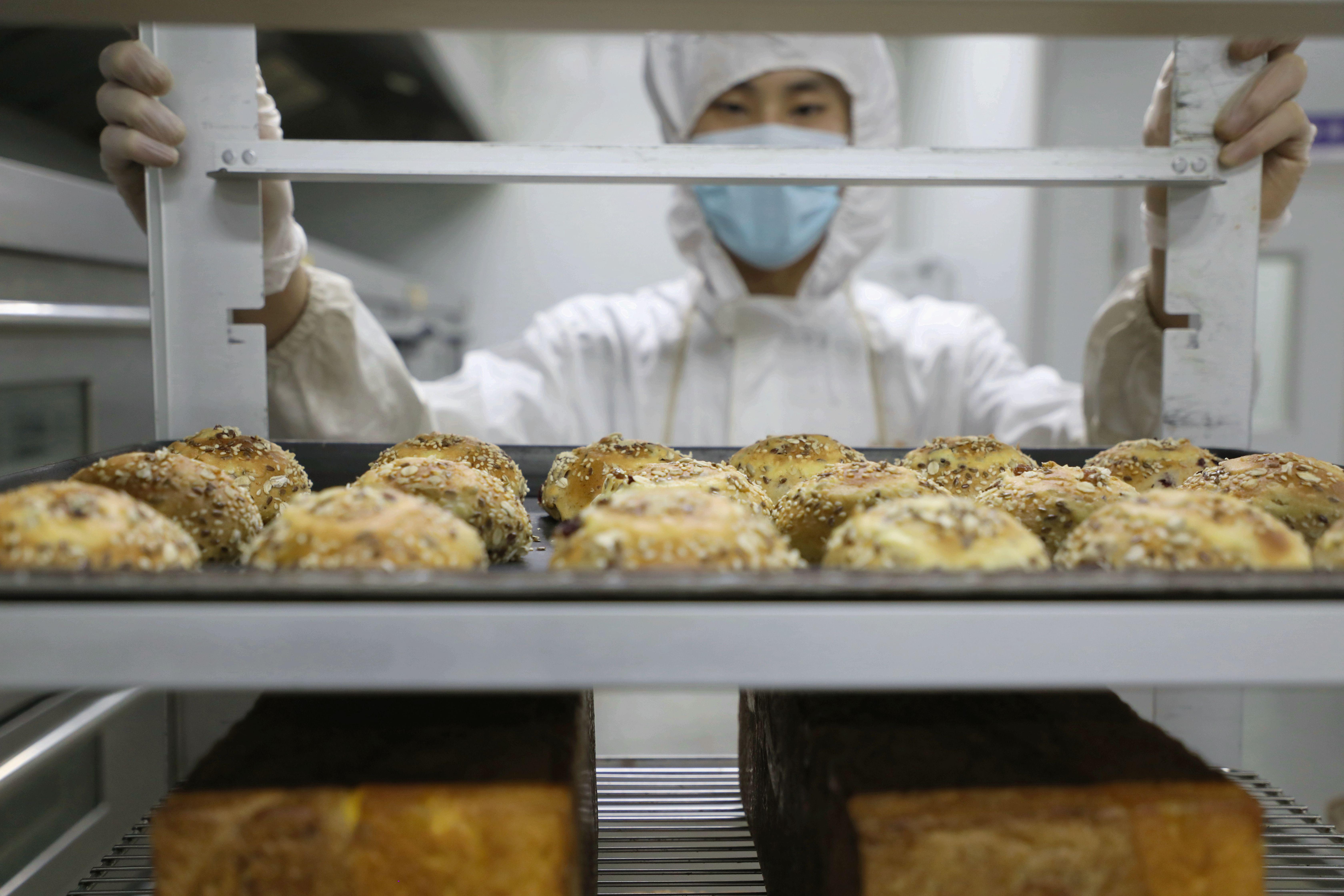 在香河县一食品厂烘焙车间，工人搬运烤制好的面包。朱钰爽摄