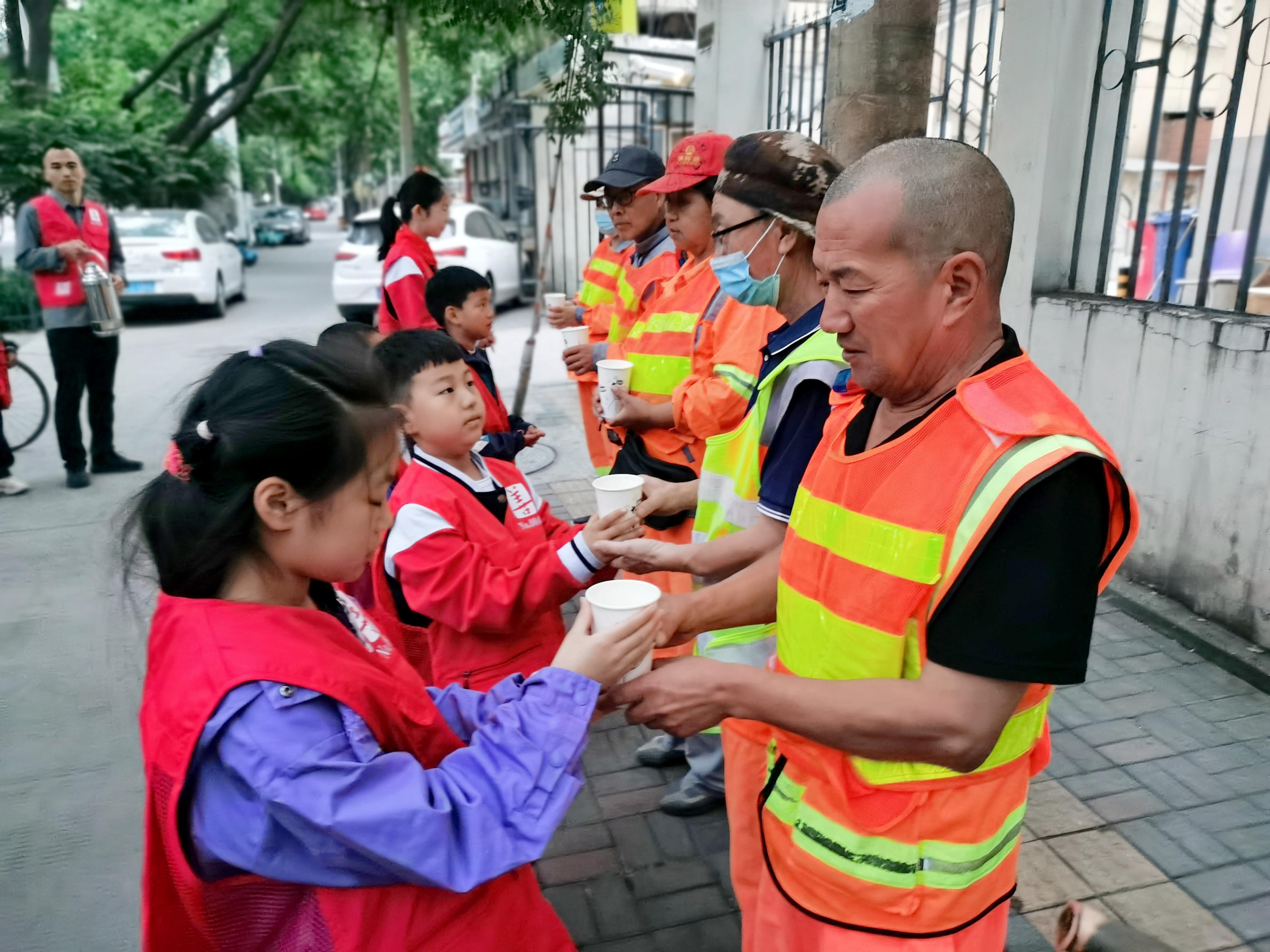 学生为环卫工人送上一杯豆浆，一声问候。石家庄市草场街小学教育集团供图