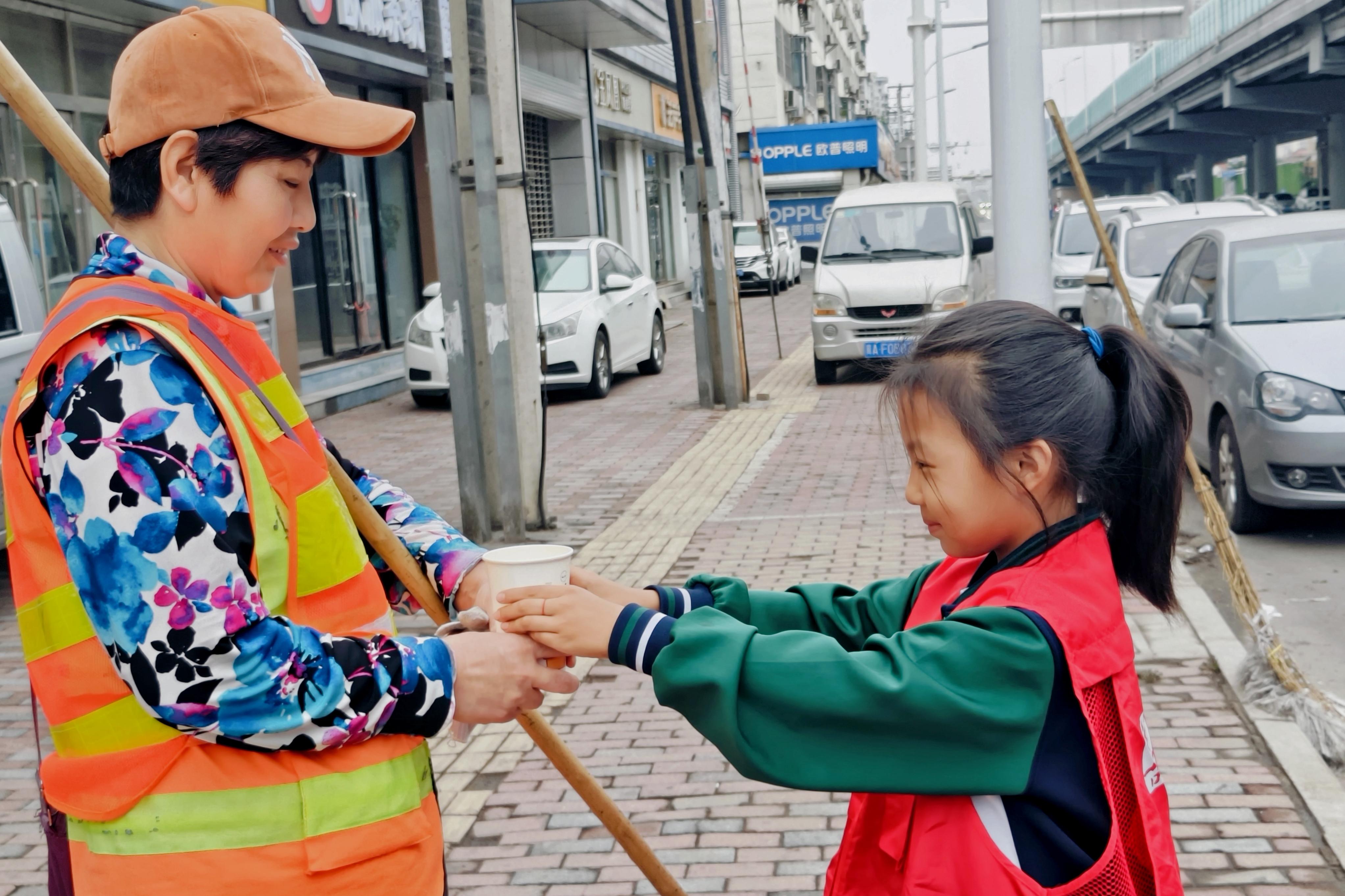 学生为清早忙碌的环卫工人送豆浆。 石家庄市草场街小学教育集团供图