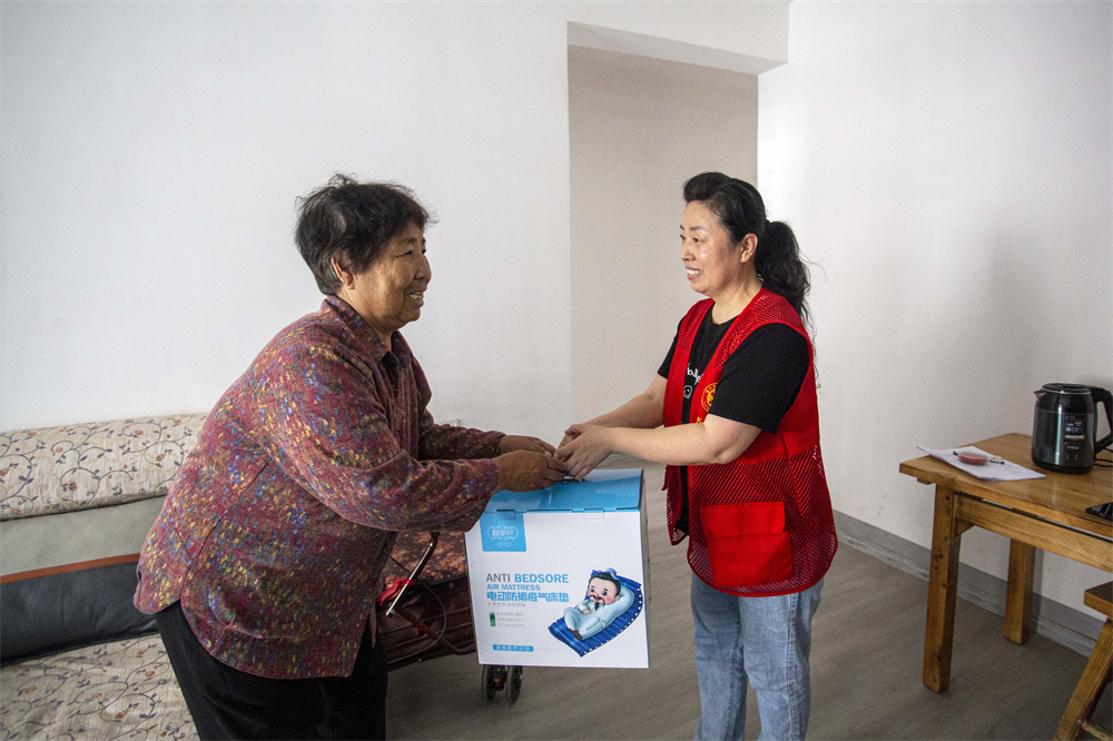 在河北省邯鄲市復興區彭家寨鄉西小屯社區，志願者為80多歲的曹桂珍老人送去防痔瘡墊。聶長青攝