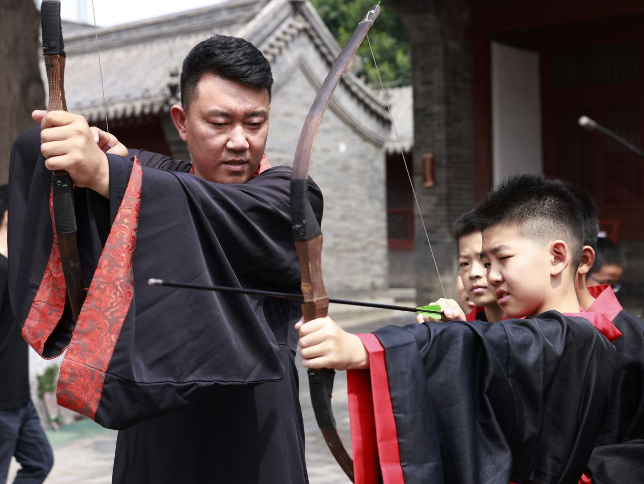 學生們手持弓箭，擺出姿勢，練習射五毒。楊晨攝
