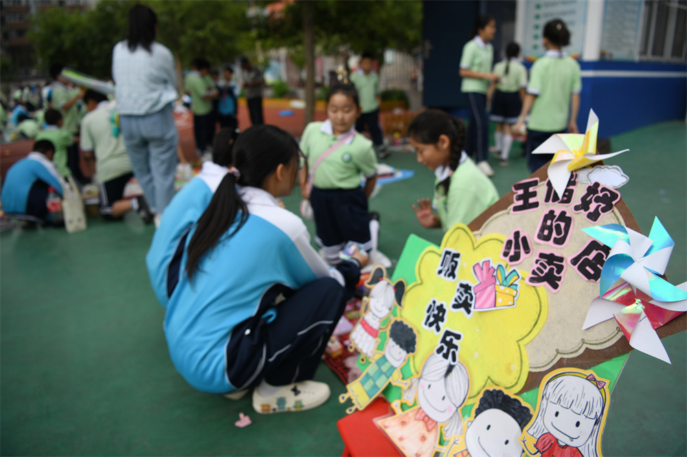 在承德市双桥区魁星园小学，学生们在摊位前挑选、购买自己喜爱的义卖物品。 陈琦嘉摄