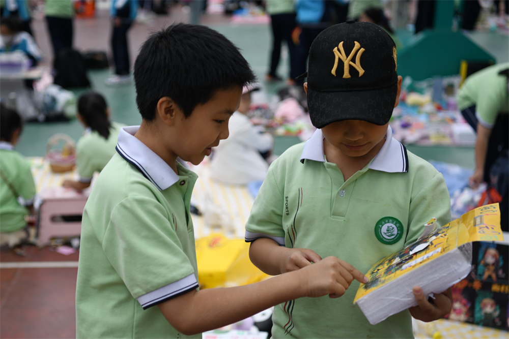 在承德市双桥区魁星园小学，学生们在摊位前挑选、购买自己喜爱的义卖物品。 陈琦嘉摄