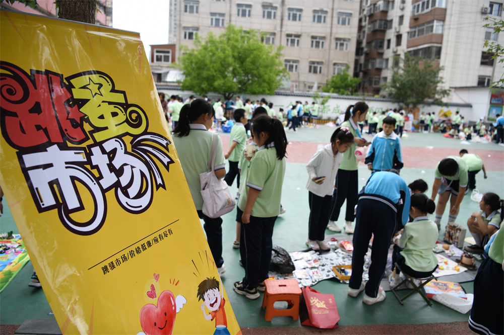 在承德市双桥区魁星园小学，学生们在摊位前挑选、购买自己喜爱的义卖物品。 陈琦嘉摄