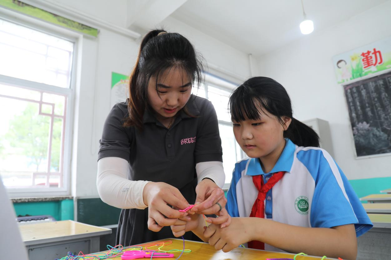 6月6日，易县大龙华中心小学教师指导学生编织五彩绳。王健摄