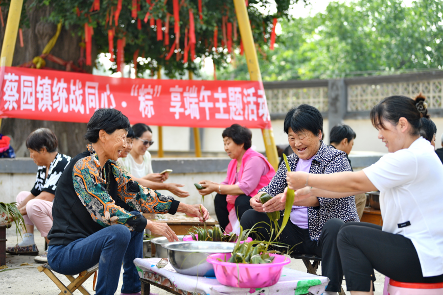 6月6日，在迁安市蔡园镇马官营村千年白果树下，村民正在包粽子。梁玉水摄