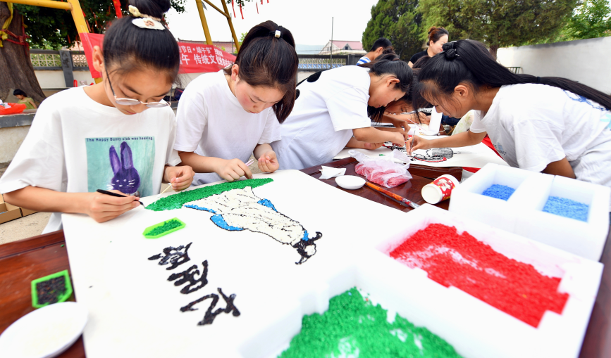 6月6日,在遷安市蔡園鎮馬官營村千年白果樹下,孩子們正在制作端午主題的種子粘貼畫。梁玉水攝