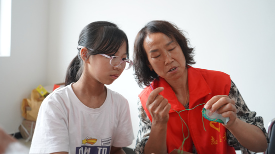 学生在新时代文明实践志愿者指导下缝制香包。唐笛摄