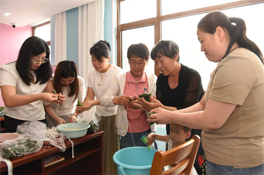 社区居民与工作人员交流包粽子技巧。时萍萍摄