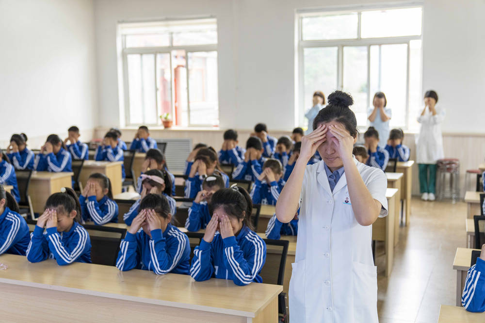 在秦皇岛市山海关区古城小学，秦皇岛市工人医院眼耳鼻喉科医务人员带领学生们做眼保健操。郭楠摄