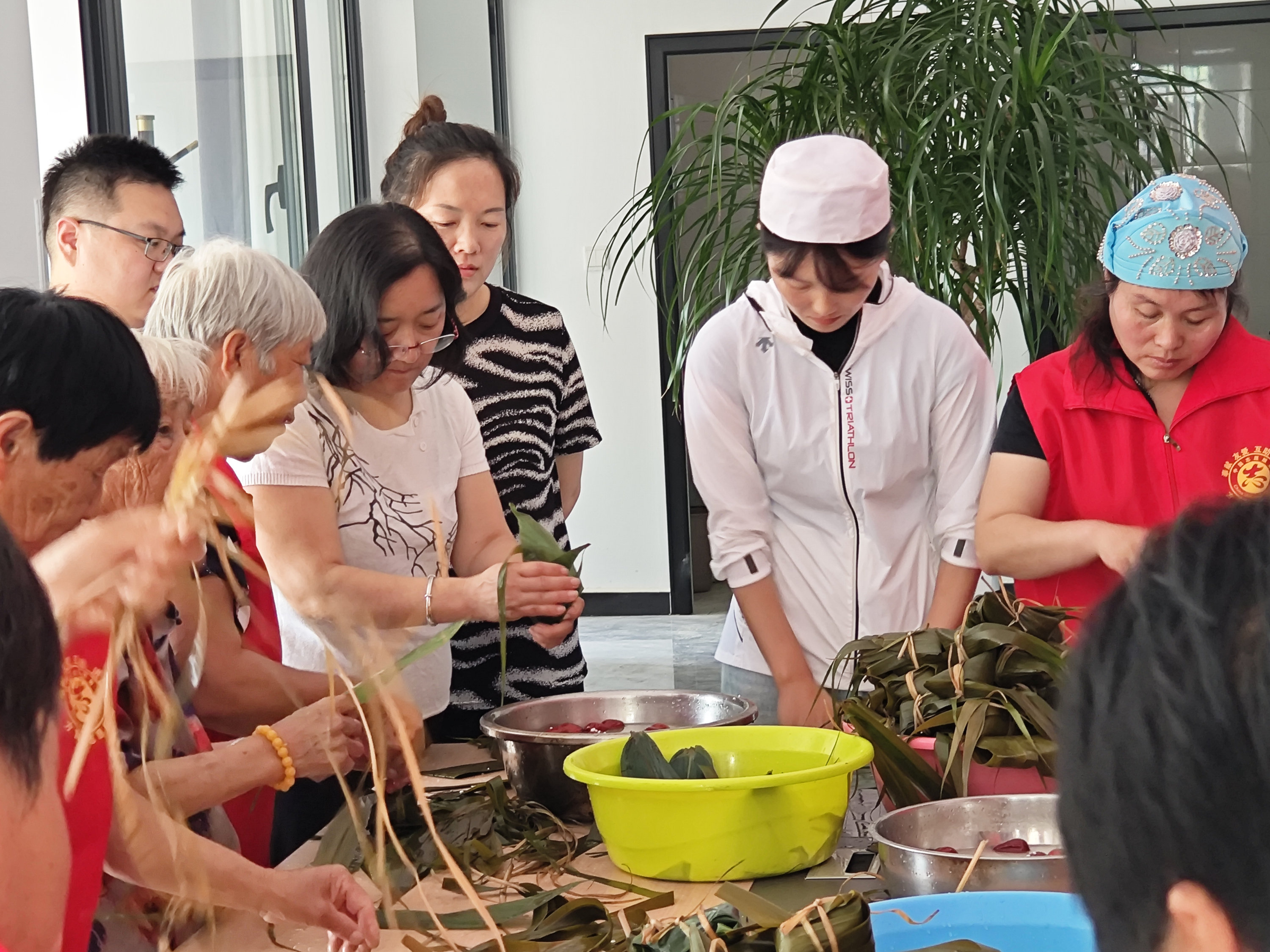 6月6日,在高碑店市方官鎮方官村互助幸福院,志願者與村民圍在一起包粽子。薛魯源攝