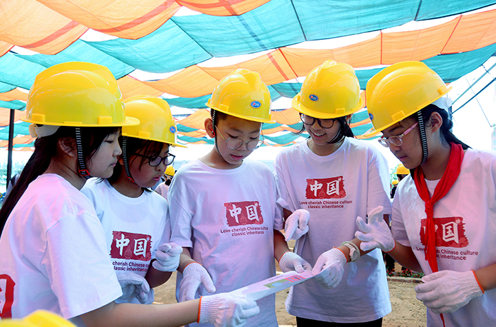 劳动研学实践体验活动现场，学生们一起研究微型景观建造图纸