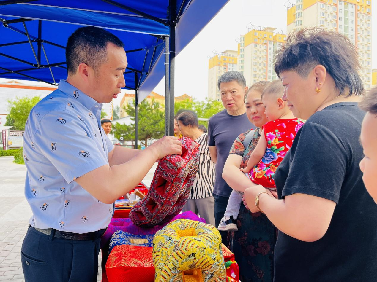 非遗传承人正在向群众介绍耳枕。李金璐摄