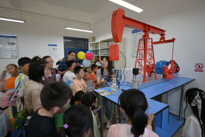 小學生在燕山大學與大學生互動體驗採油設備的原理演示。秦皇島市北戴河區委宣傳部供圖
