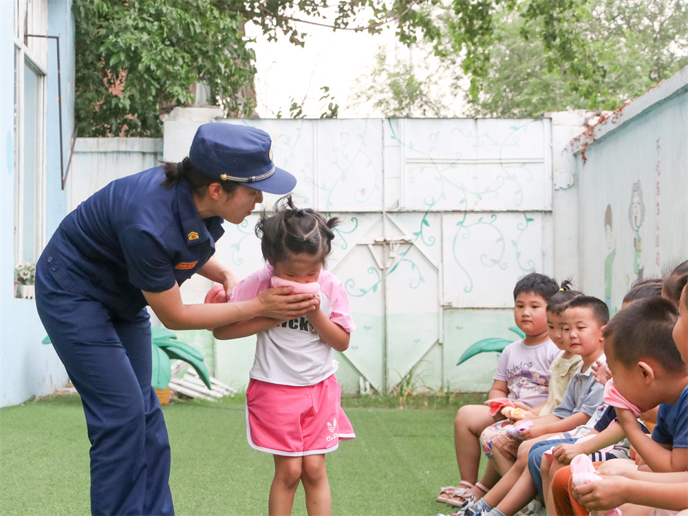 6月13日,在河北省高碑店市洪桥幼儿园开展的消防安全培训中,消防救援大队宣传员白凤正在向小朋友们讲解在火灾逃生中毛巾的正确使用方法。祖嘉诚摄