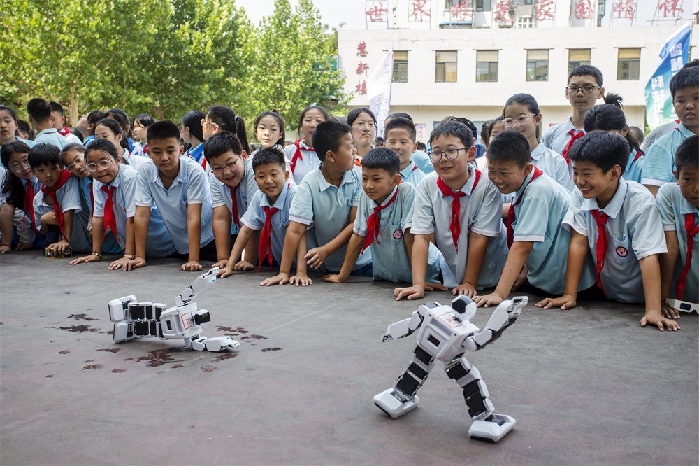 6月14日,河北省邯郸市复兴区前进小学操场,学生们在观看机器人跳舞。聂长青摄