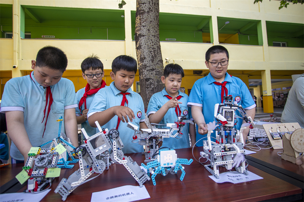6月14日，河北省邯郸市复兴区前进小学操场，学生们在体验和参与各种类型的机器人。聂长青摄