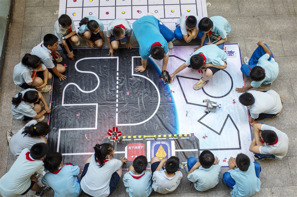 6月14日,河北省邯郸市复兴区前进小学操场,学生们在体验和参与机器人演示。聂长青摄