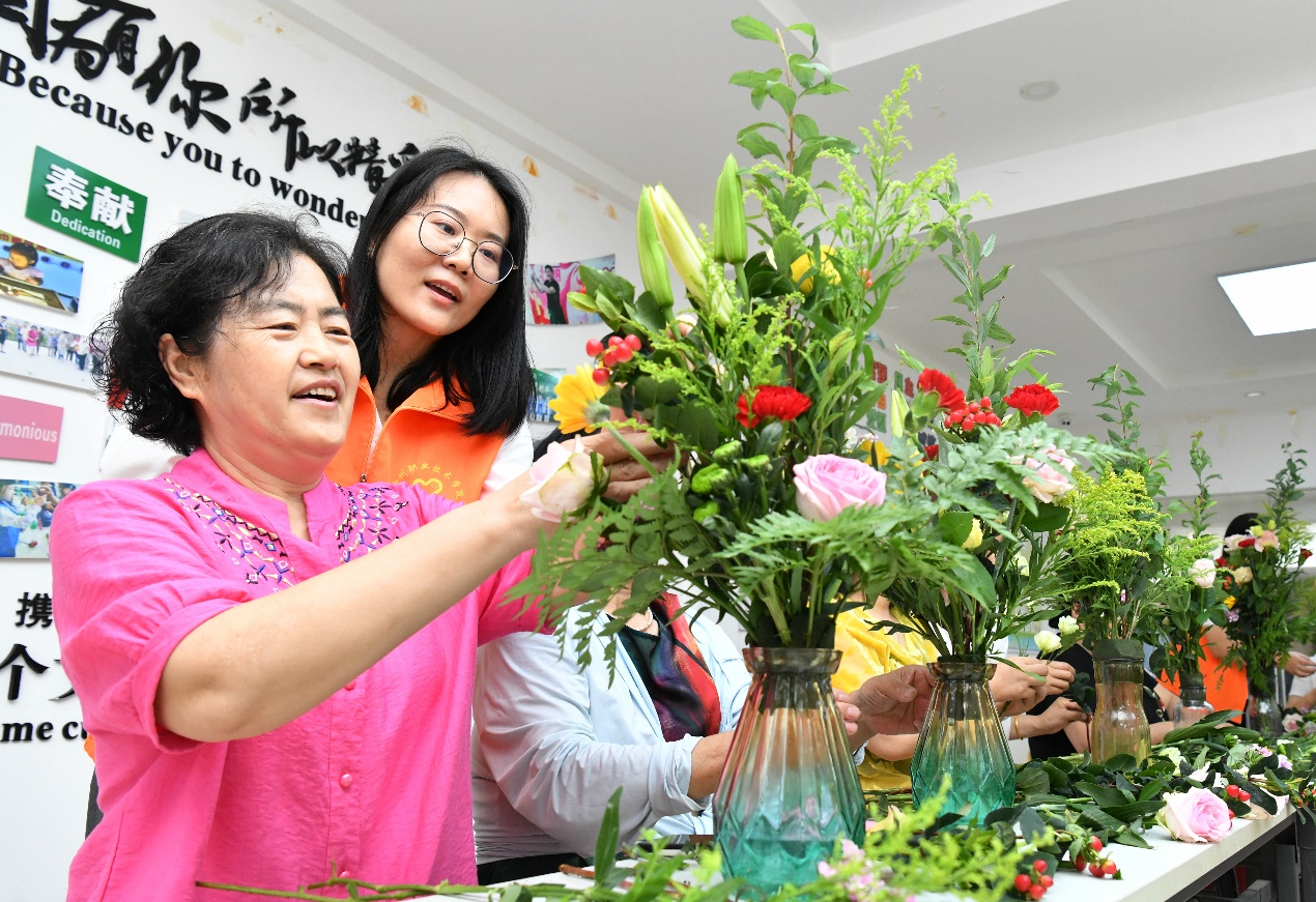 6月15日，在沧州市凤凰城社区新时代文明实践站，沧州职业技术学院的学生正在指导居民学习插花。苑立伟摄